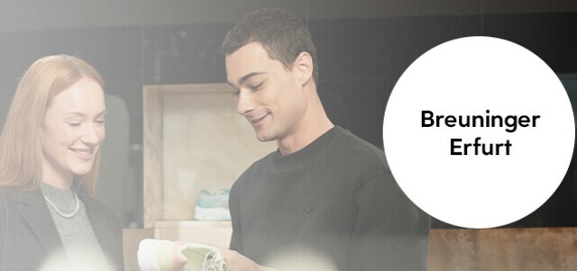 Zwei Personen stehen im Gespräch in einem Modegeschäft; rechts ein runder Hinweis mit der Aufschrift „Breuninger Erfurt“, Verkaufsfläche und Kund:innen unscharf im Hintergrund.