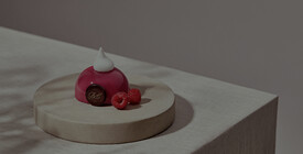 Nürnberg Elegantes Dessert in glänzendem Rot mit Himbeeren, garniert auf einer runden Platte.